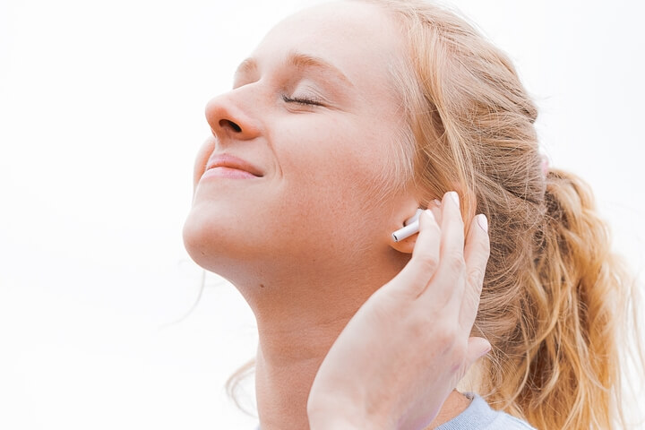 Joven escuchando música de alta calidad en sus auriculares inalámbricos AirPods de Apple para iPhone.