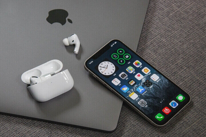 iPhone y AirPods sobre una Macbook de Apple.